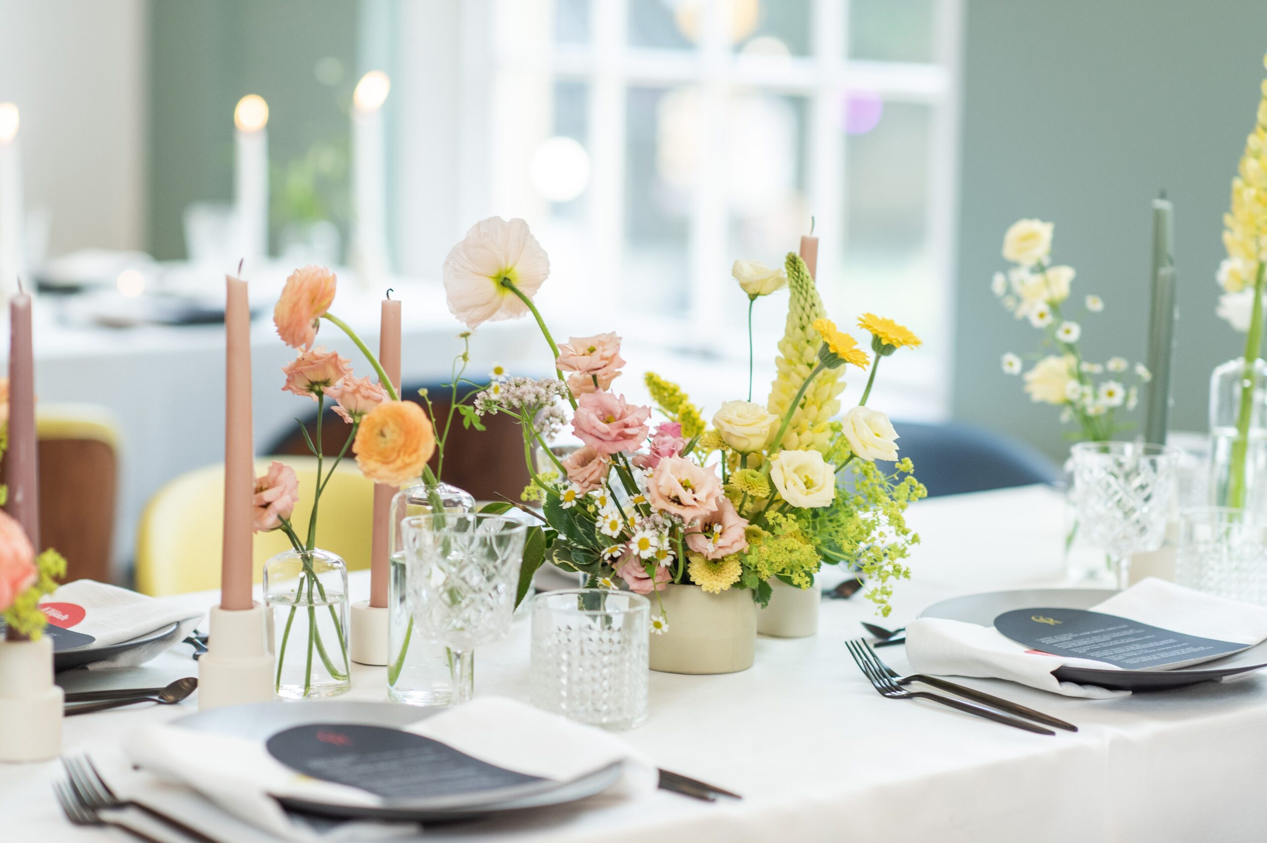 Modern wedding table setting with colourful candles & pink and green flower arrangements