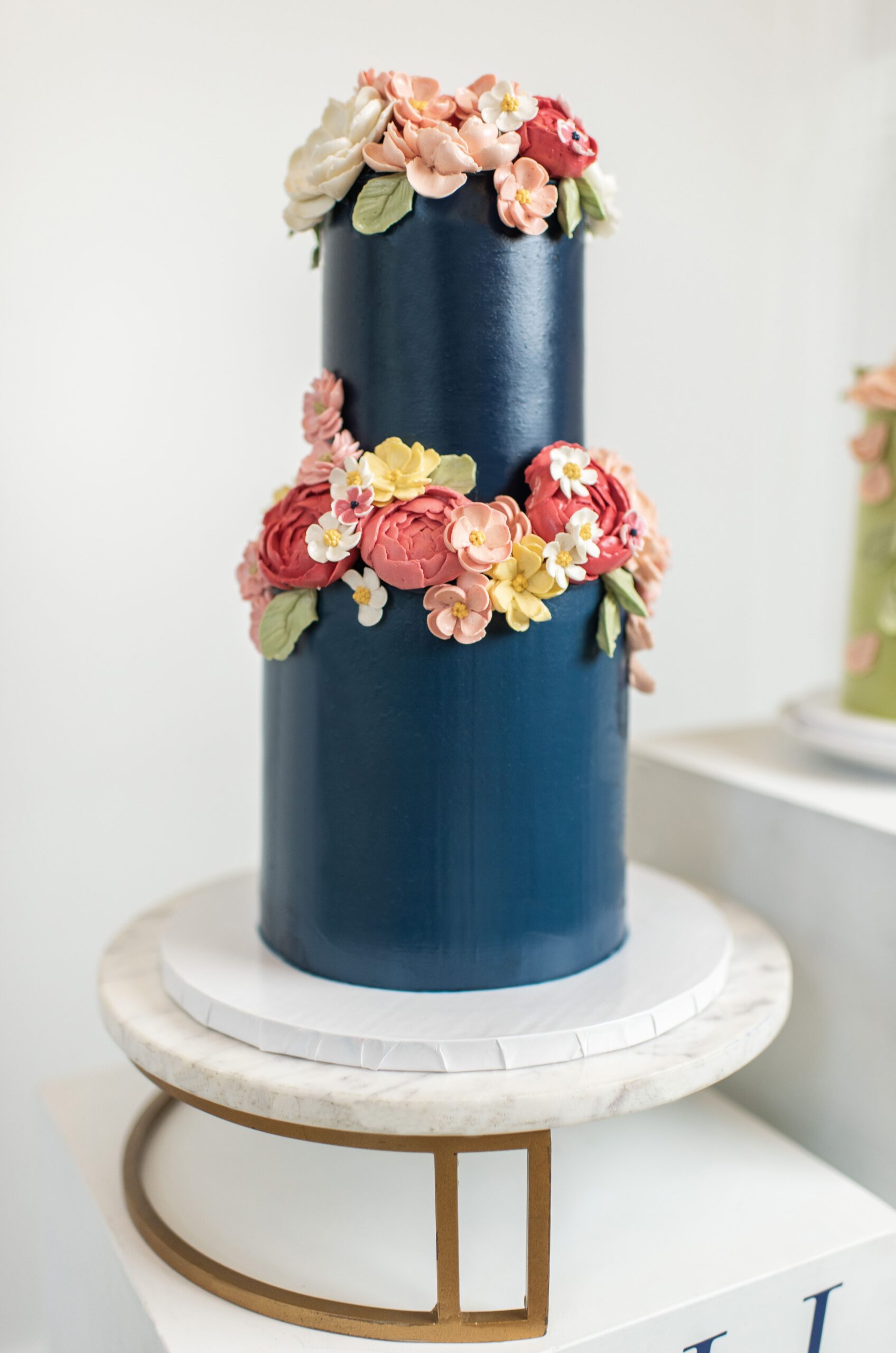 Navy blue wedding cake with pink and red butter cream flowers