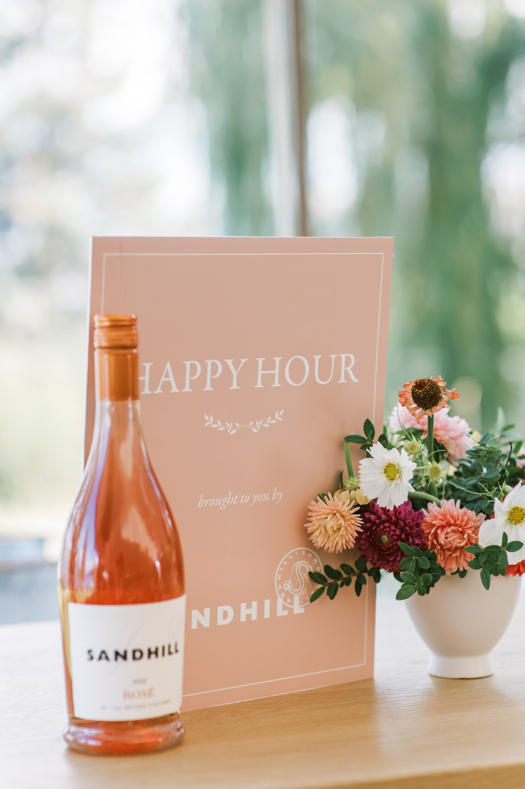 Pink bar signage with pink, burgundy and white flowers in white vase