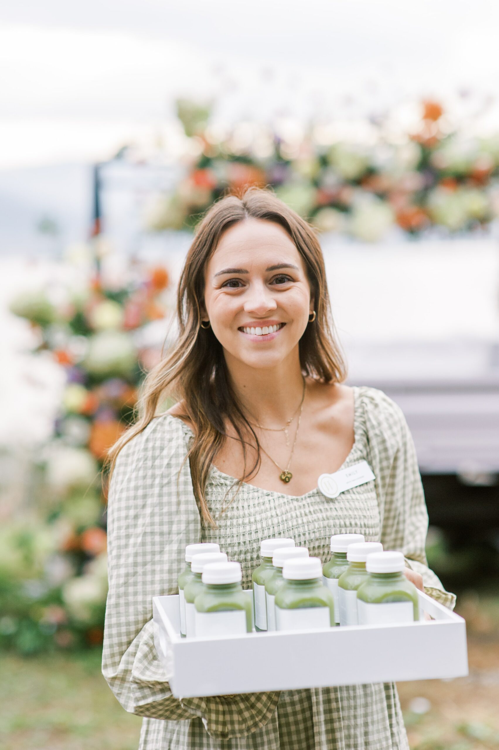 Lady in green and white dress serving green juice on white trays