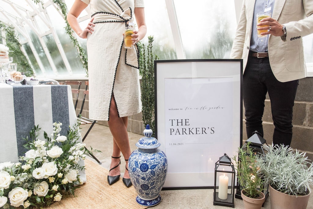 Bride and groom standing in front of welcome sign at high tea engagement party