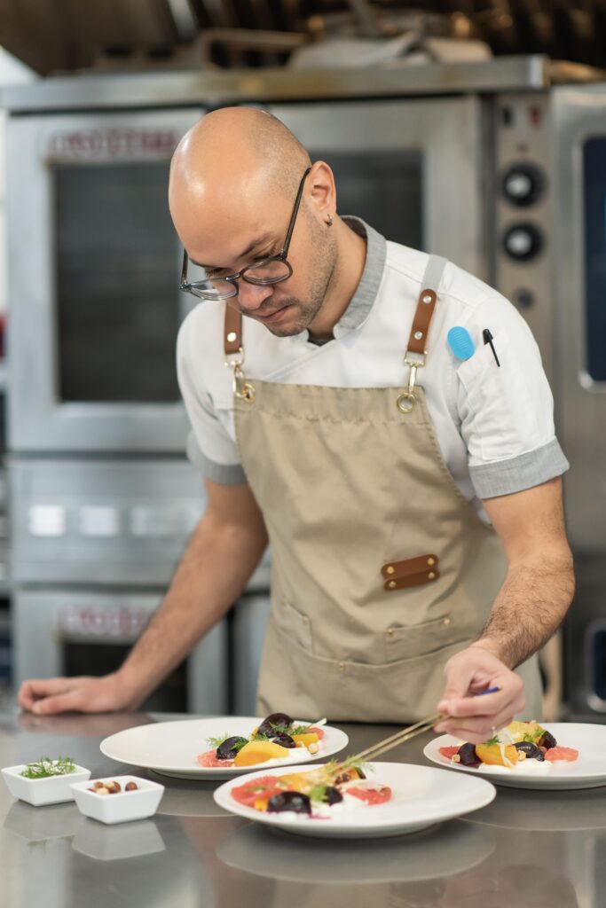 White Table catering chef preparing a plated salad with tweezers