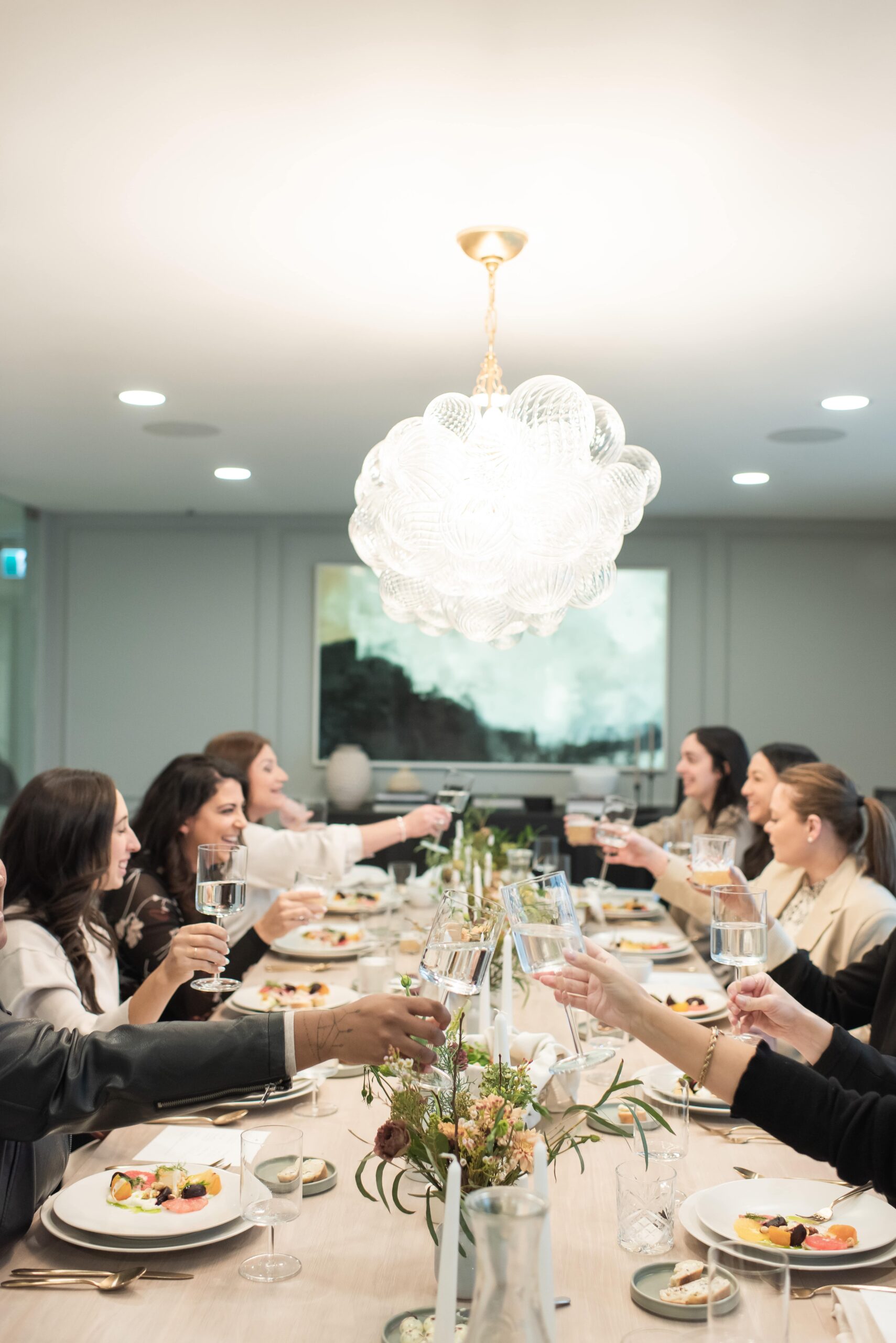 Guests at long table toasting wine glasses